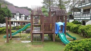 A playground with slides and climbing structures, surrounded by well-maintained grass and bushes. - E Resort (Brinchang)