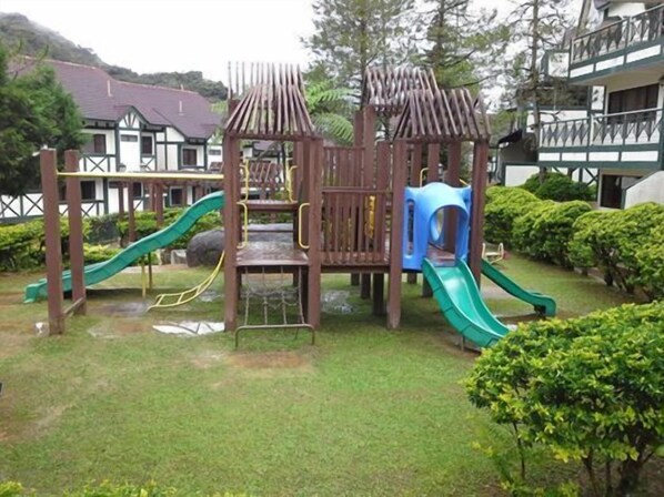A playground with slides and climbing structures, surrounded by well-maintained grass and bushes. - E Resort (Brinchang)