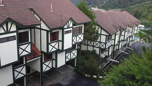 A row of traditional timber-framed buildings with red-tiled roofs, set against a mountainous backdrop. - E Resort (Brinchang)