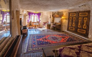 A traditional room with a large ornate rug, wooden furniture, and a stone wall.