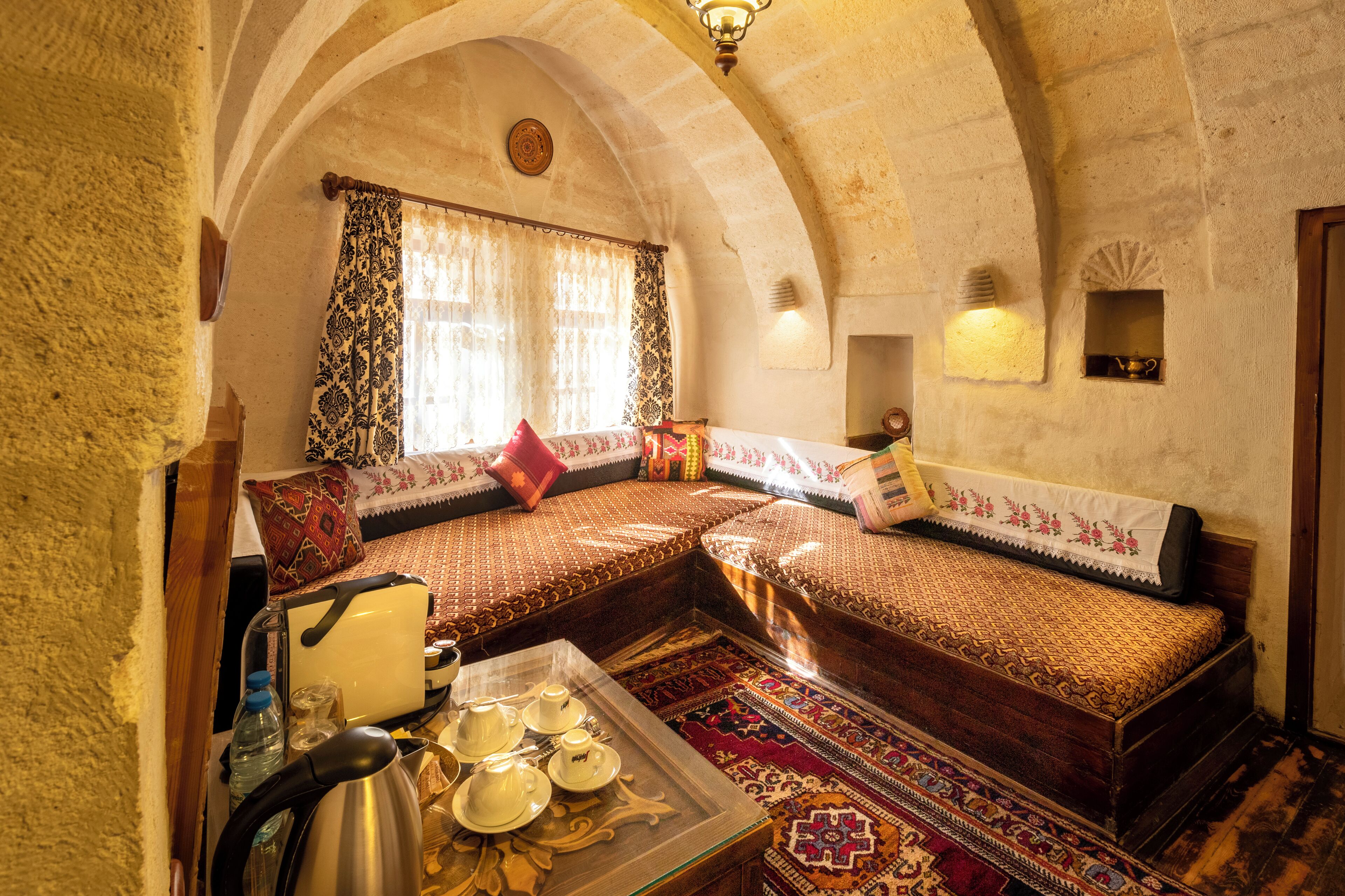 A traditional room with a sofa set, a table with tea sets, and a patterned rug.