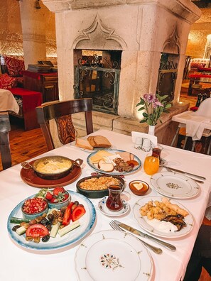 A dining table set with various dishes, a fireplace, and a flower vase.