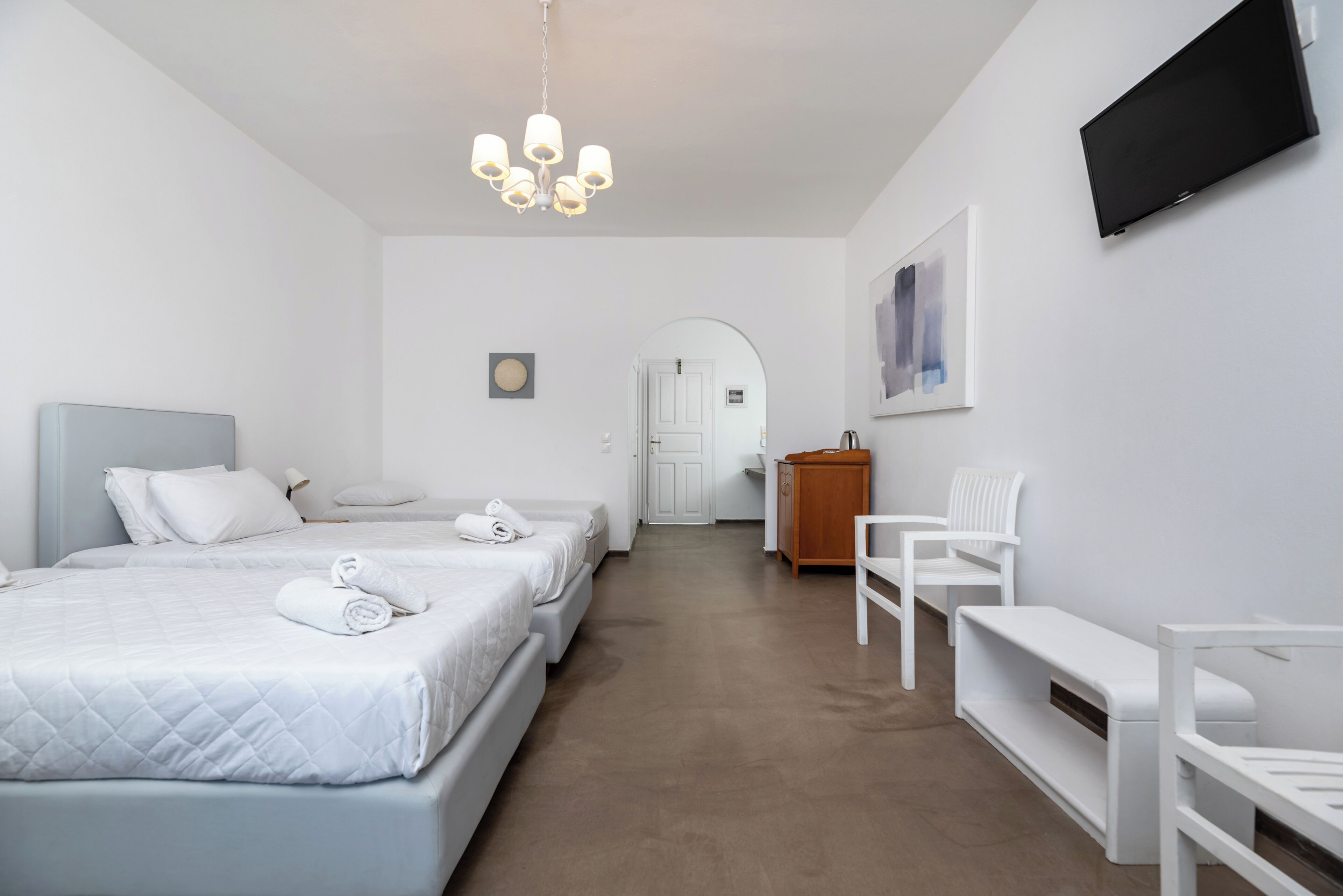 Een hotelkamer met twee bedden, een bureau, een stoel, een televisie en een deur naar een badkamer.