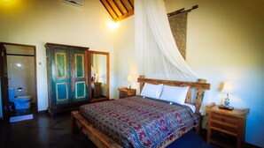 Un dormitorio con cama de madera, una mesita de noche, un armario y un baño con inodoro.