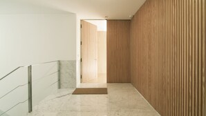 Ein moderner Flur mit Marmorboden, Holzpaneele und Glastrennwand.