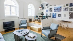 Ein modernes Wohnzimmer mit Fernseher, Sitzgelegenheiten und Kunstwerken an den Wänden.
