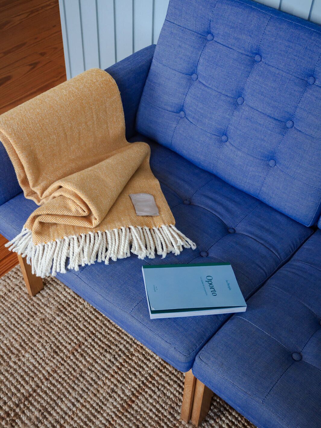 Ein blaues Sofa mit einer senfgelben Decke und einem Buch mit dem Titel 'Opato'.