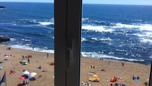 Ein Strand mit badenden Menschen und einem Blick aufs Meer.