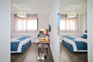 A hotel room with two beds, a dining table with breakfast items, and a TV. - Appart Hotel Le Jardin des Lettres (Tours)