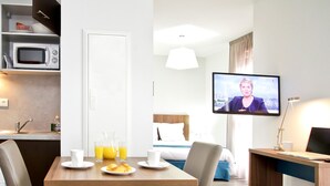 A hotel room with a dining area, a bed, a TV, and a desk with a computer.