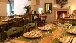 A dining area with tables set for a meal, a fireplace, and a view of the dining room through an arched doorway. - Masseria Narducci (Fasano)