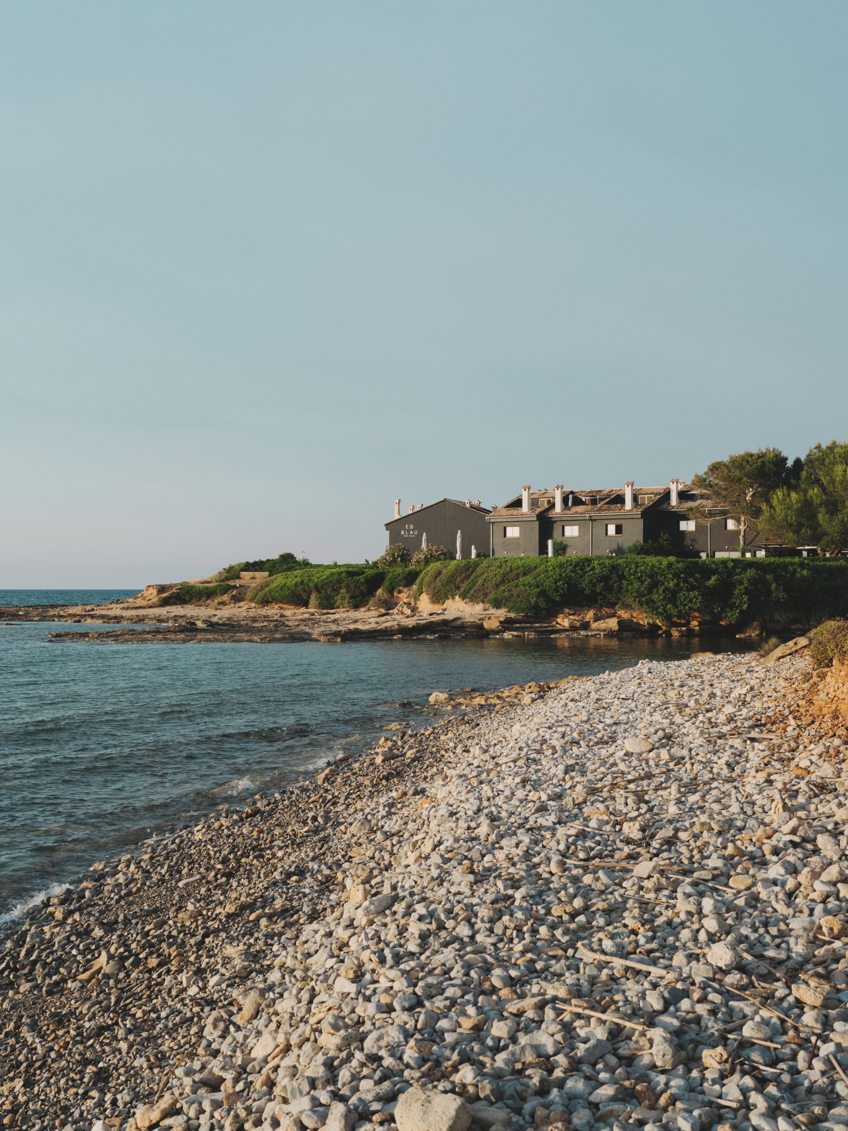 A coastal property with a rocky beach and a building with multiple levels.
