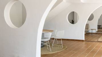 Un interior moderno con paredes blancas, círculos recortados, una mesa de madera y sillas de estructura metálica.