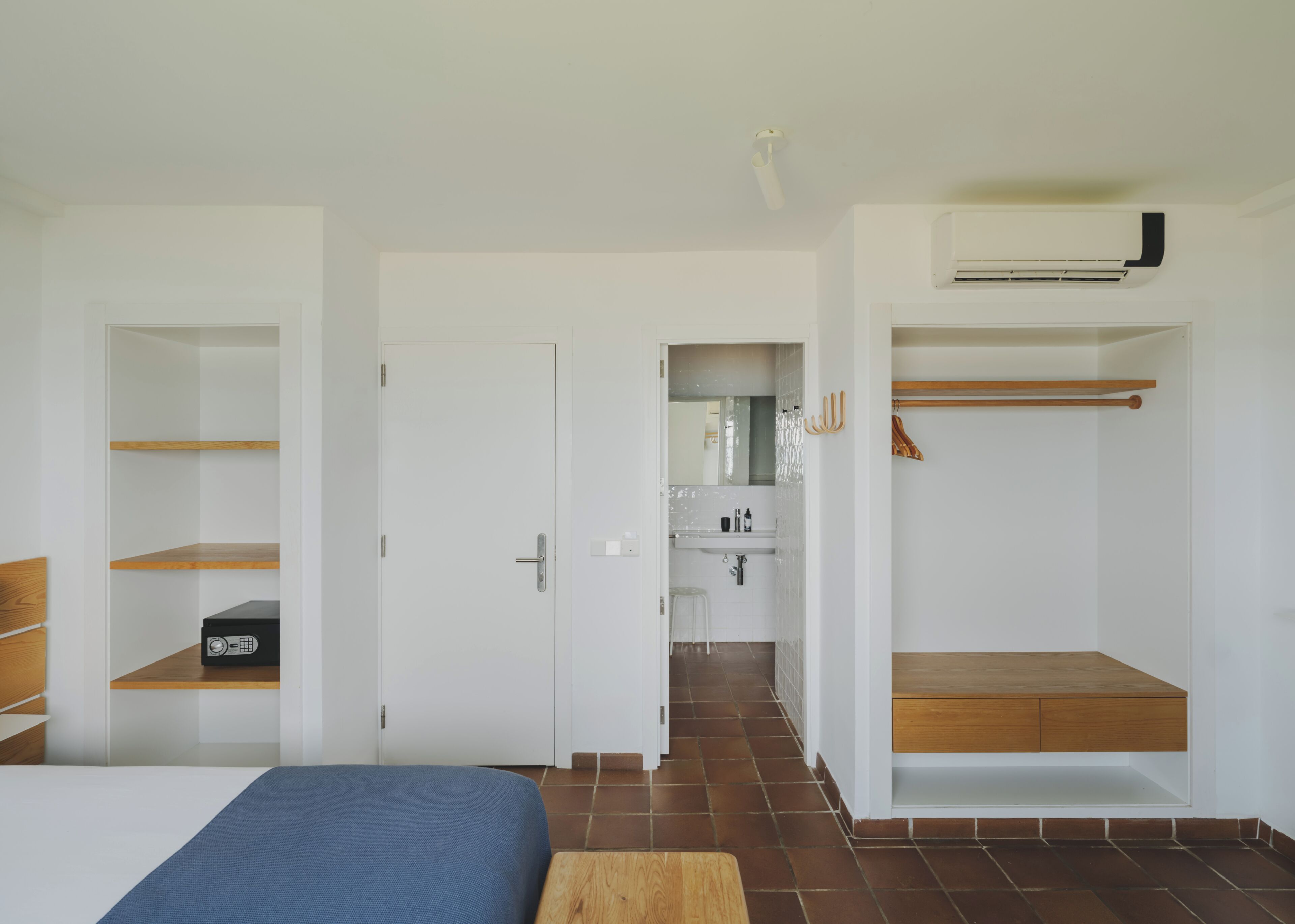Une chambre à coucher avec un lit, une armoire et une salle de bain visible à travers une porte ouverte.