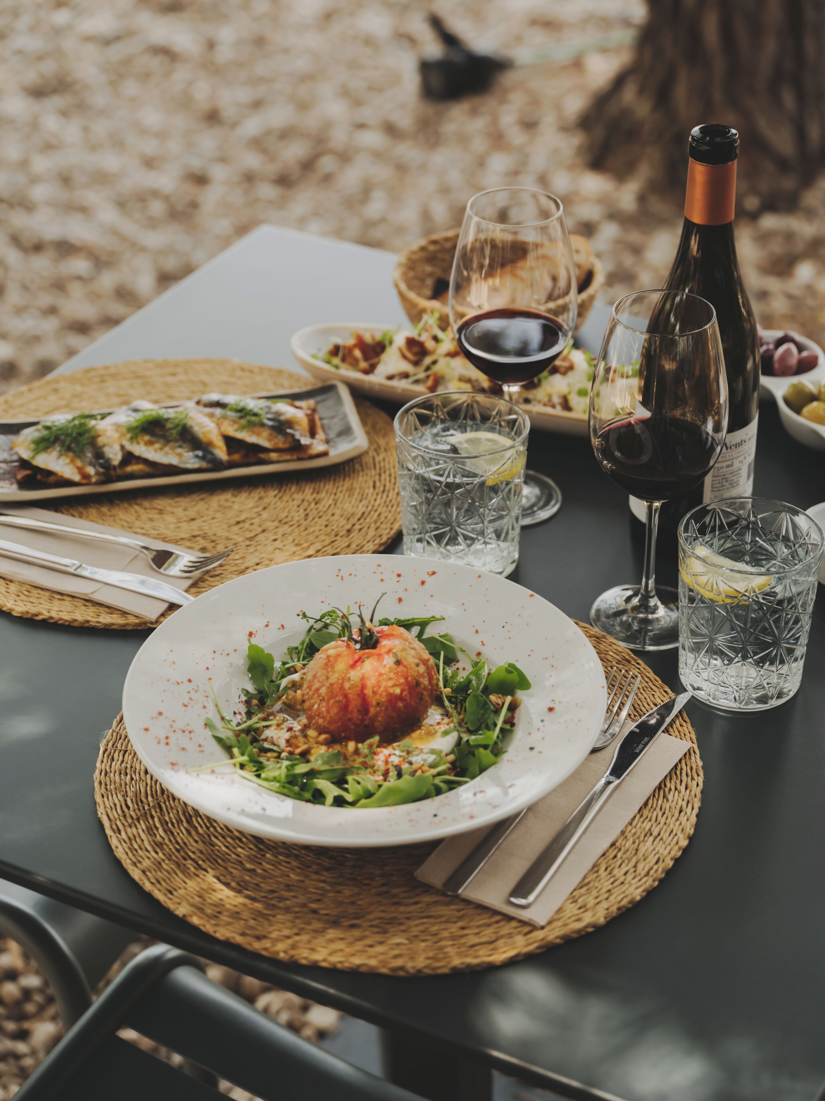 A table set with a plate of food, a bottle of wine, and glasses.