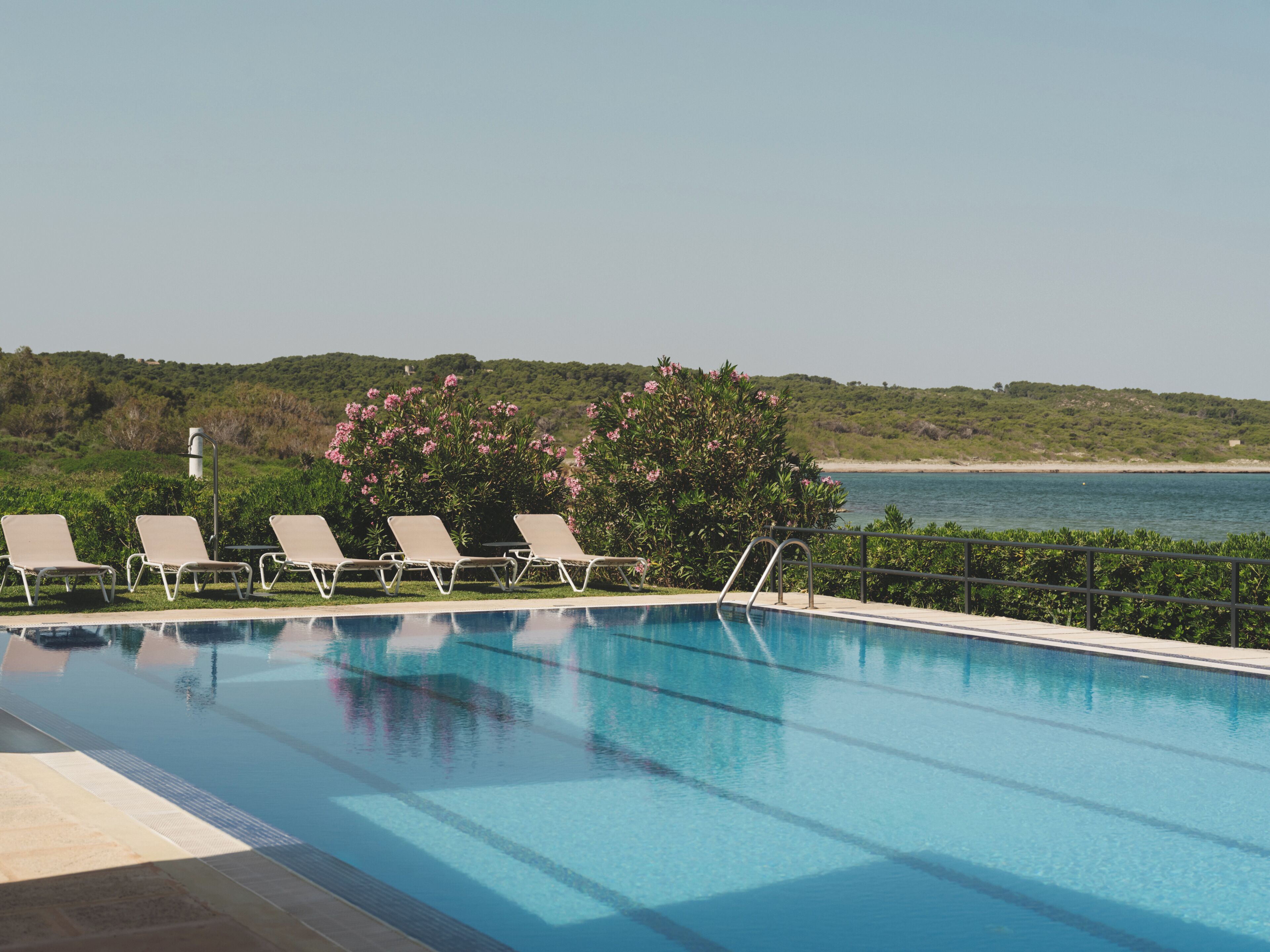 A swimming pool with lounge chairs and a view of the sea.