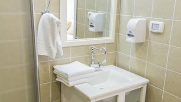 A bathroom with a white sink, a mirror, a towel rack, and a soap dispenser.