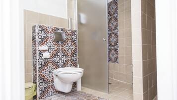 A bathroom with patterned tiles, a toilet, and a shower area.