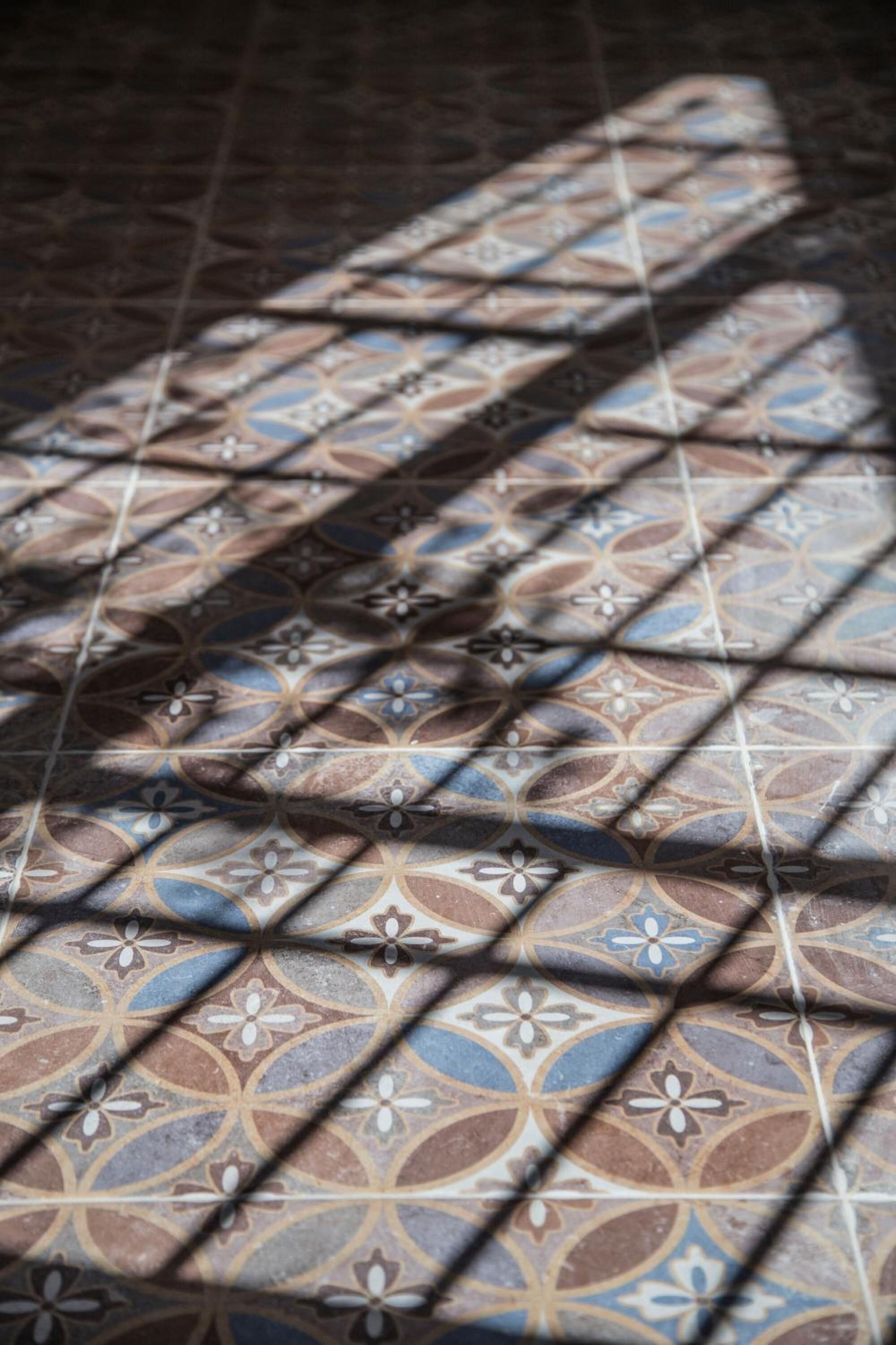 A close-up of a patterned tile floor with geometric shapes and floral motifs.