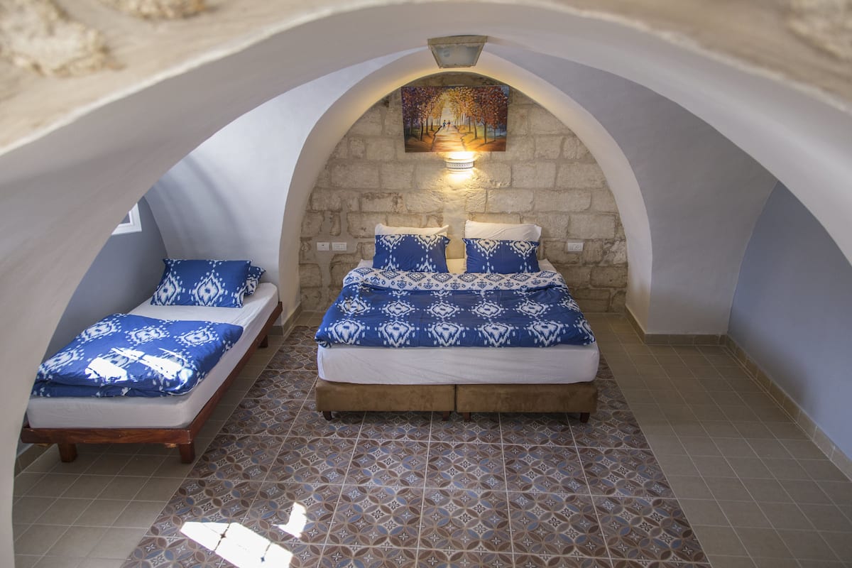 A room with a bed, a smaller bed, and a wall-mounted light fixture.