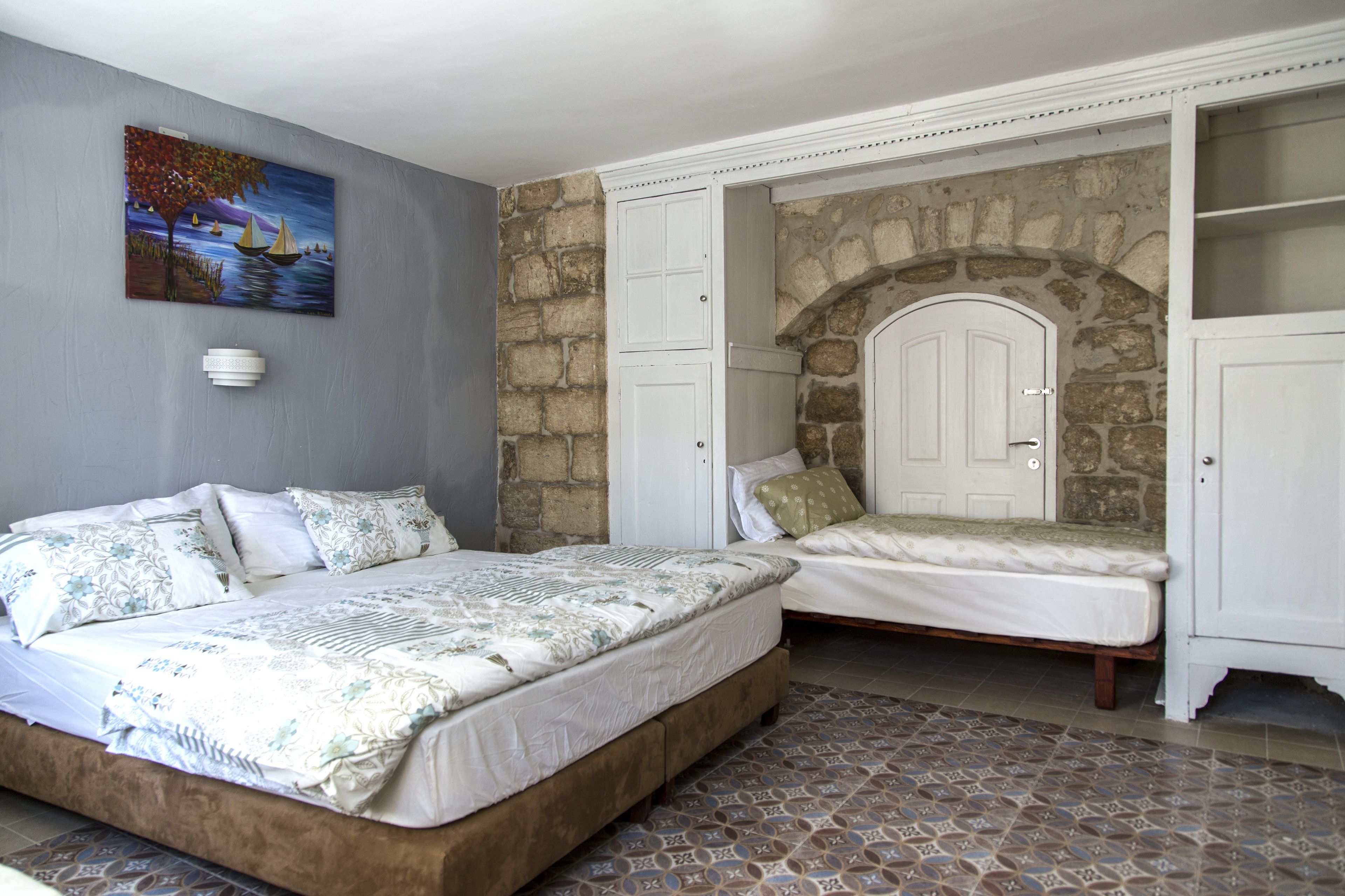Quarto com duas camas, parede de pedra e um quadro na parede.