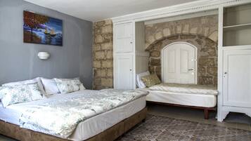 Quarto com duas camas, parede de pedra e um quadro na parede.