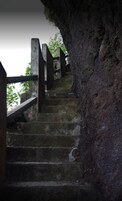 A set of stone stairs with wooden railings, leading up a rocky path.