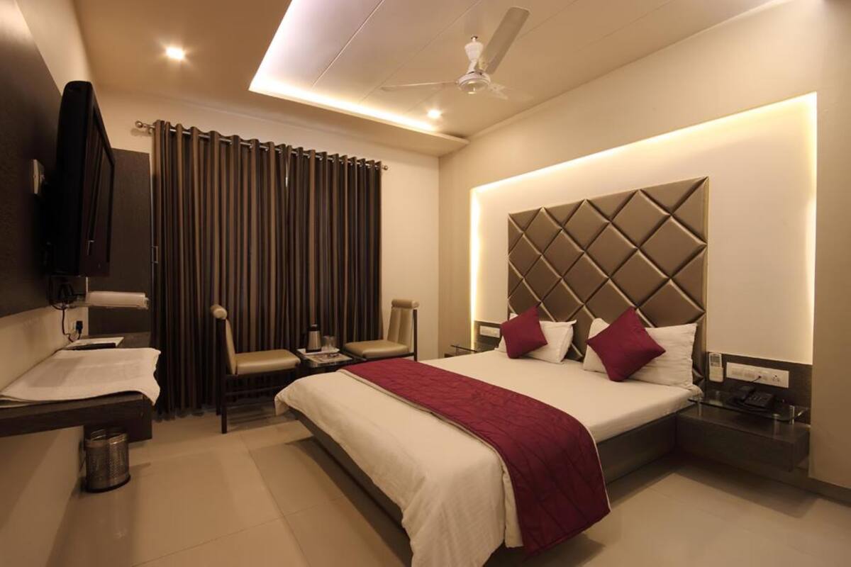 A modern hotel room with a large bed, a desk, a chair, and a television.
