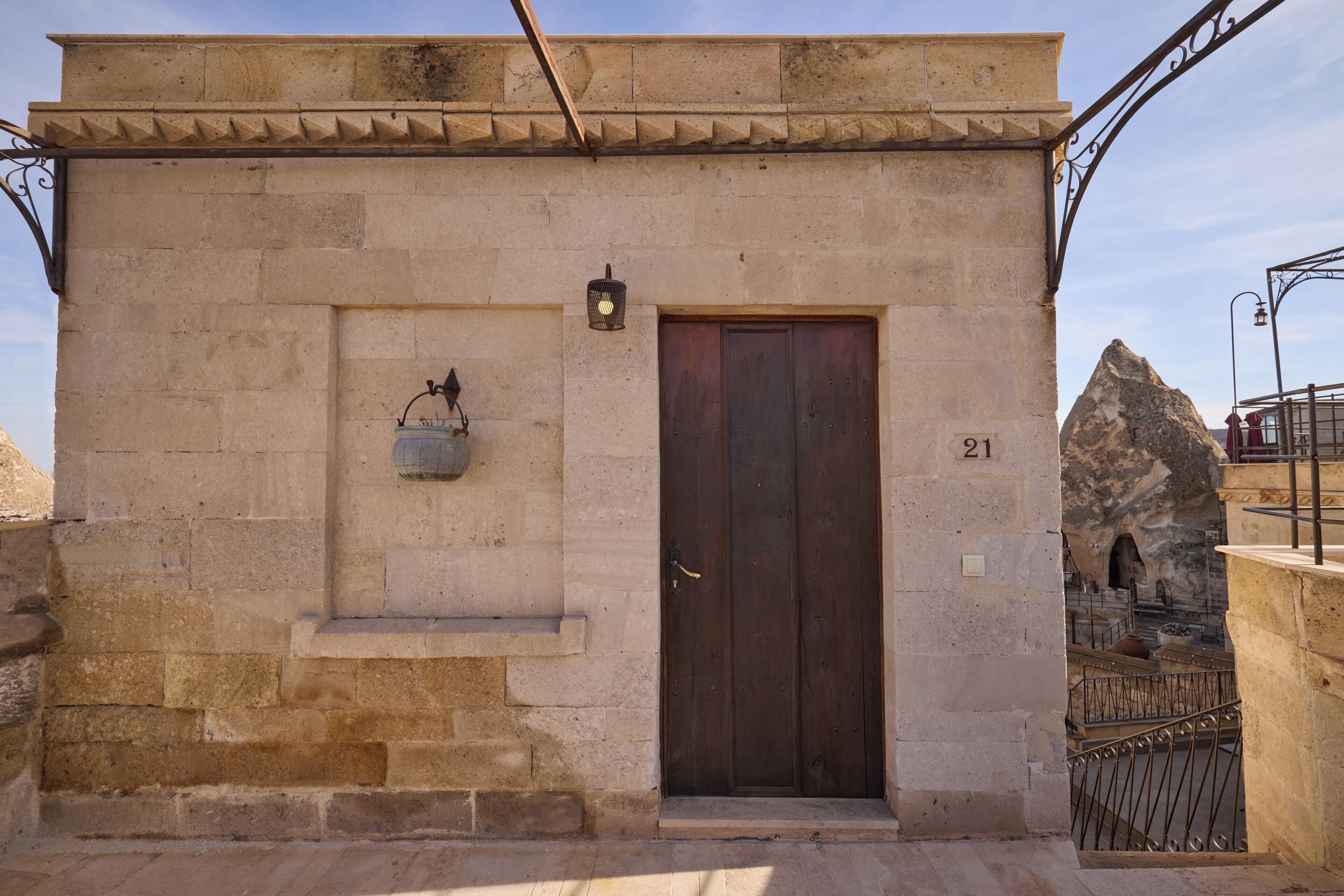 A stone building with a wooden door, numbered 21, and a hanging light fixture.