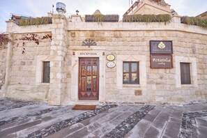 A stone building with a reception area, a rooftop garden, and a sign for 'Veranda rooftop'.