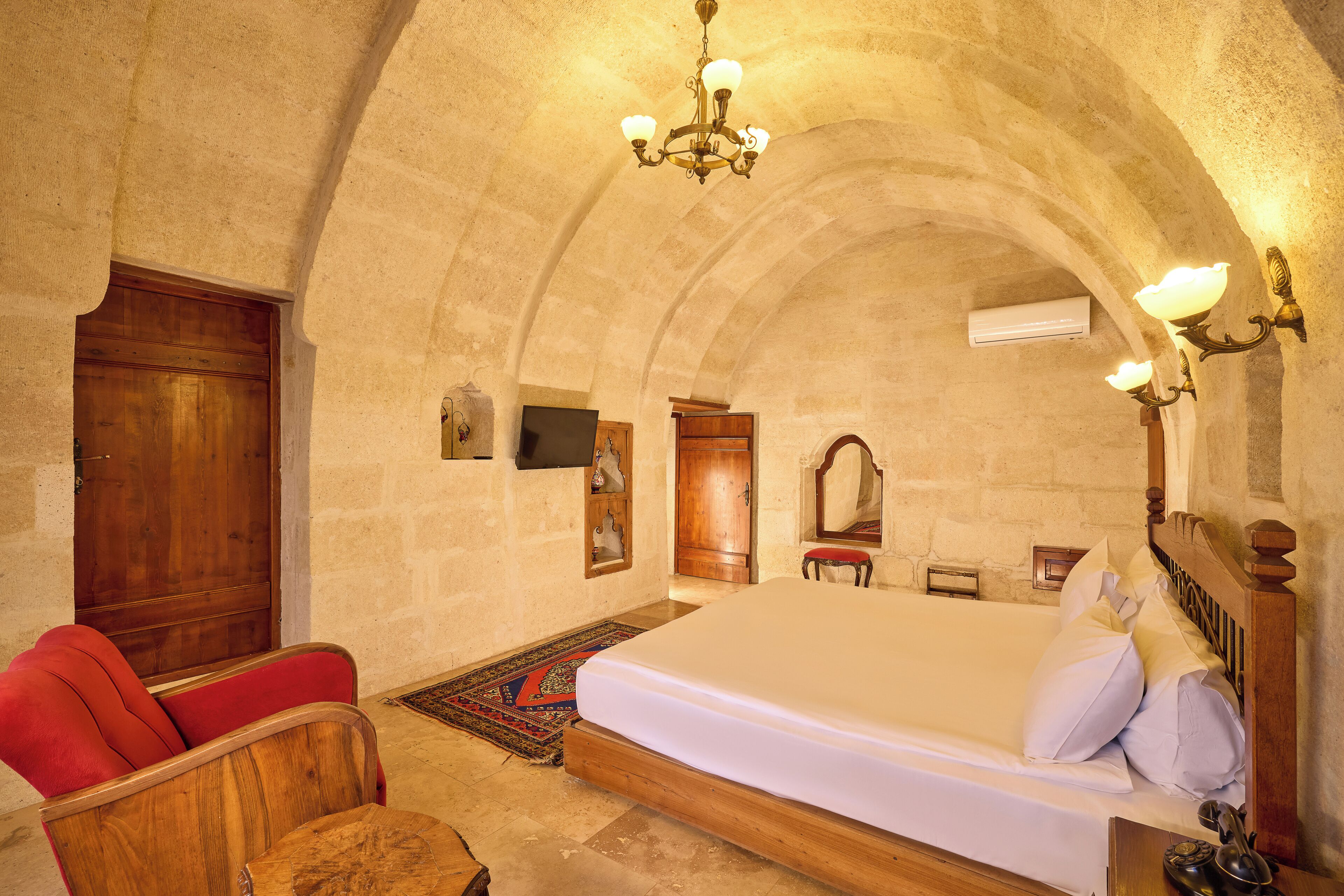 A bedroom with a large bed, wooden furniture, and a chandelier.