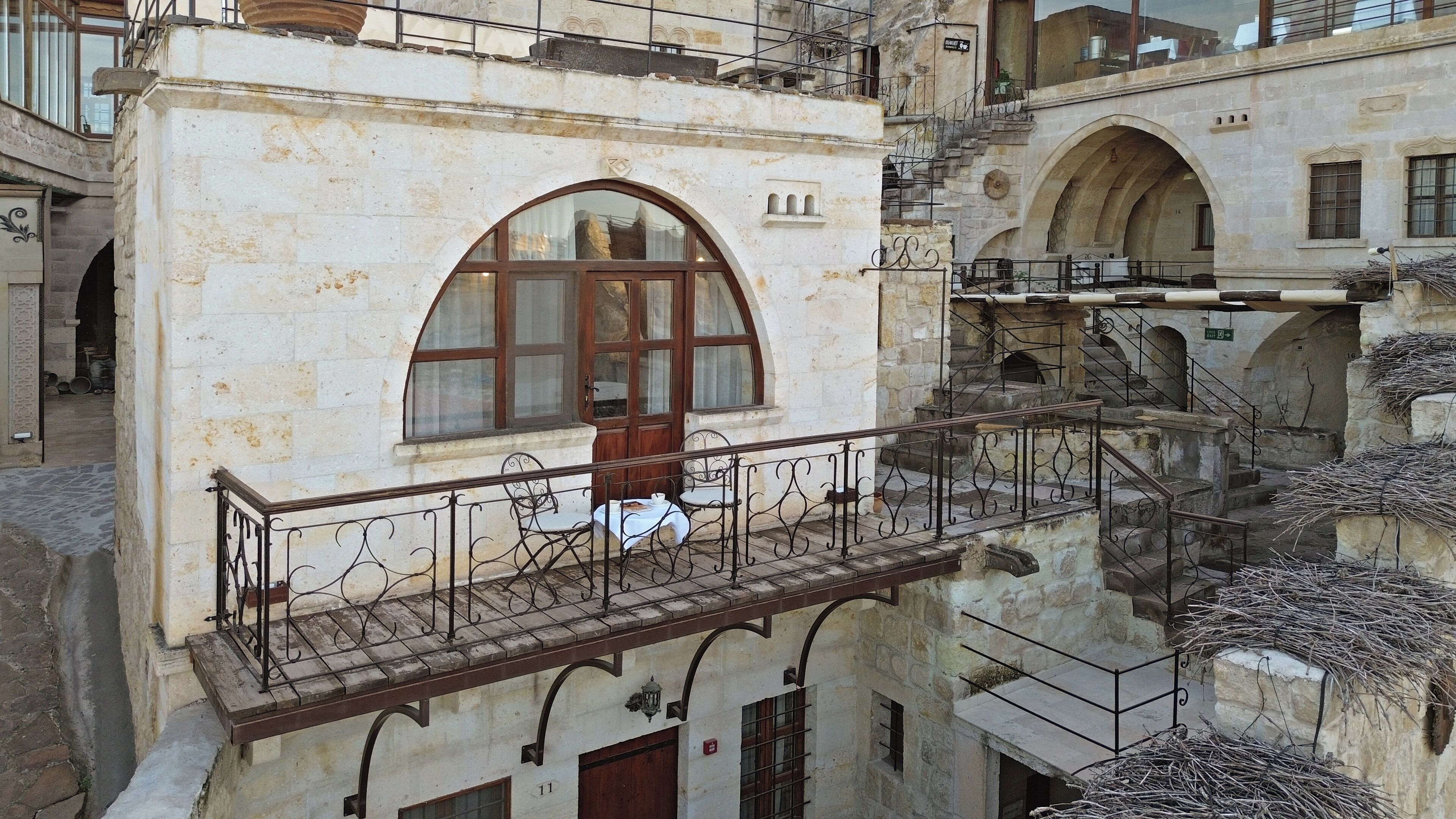 Un edificio histórico con balcón, muros de piedra y ventanas de arco.
