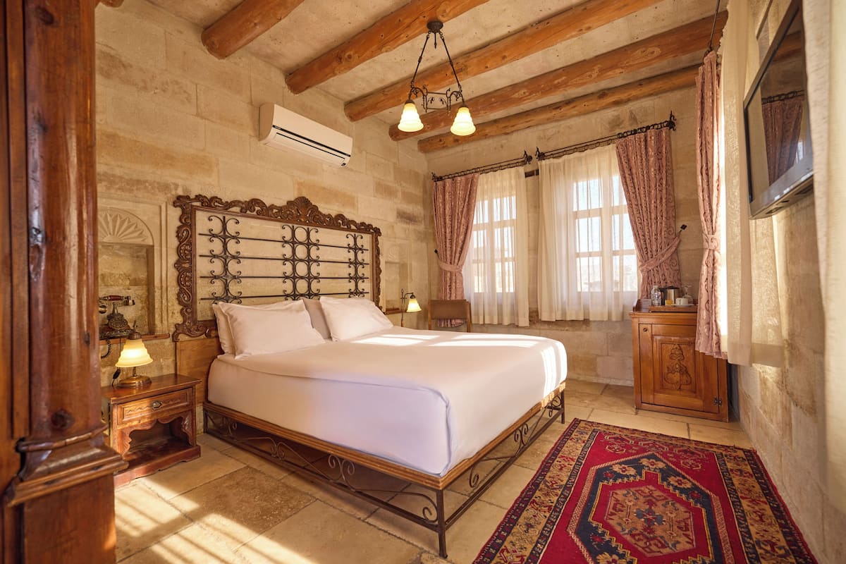 A bedroom with a wooden bed, a nightstand, a lamp, a dresser, and a patterned rug.