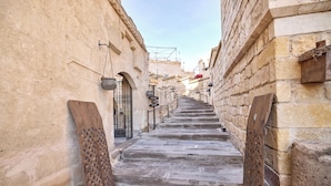 Una estrecha escalera de piedra en un edificio histórico, con barandillas de metal y puertas de madera.