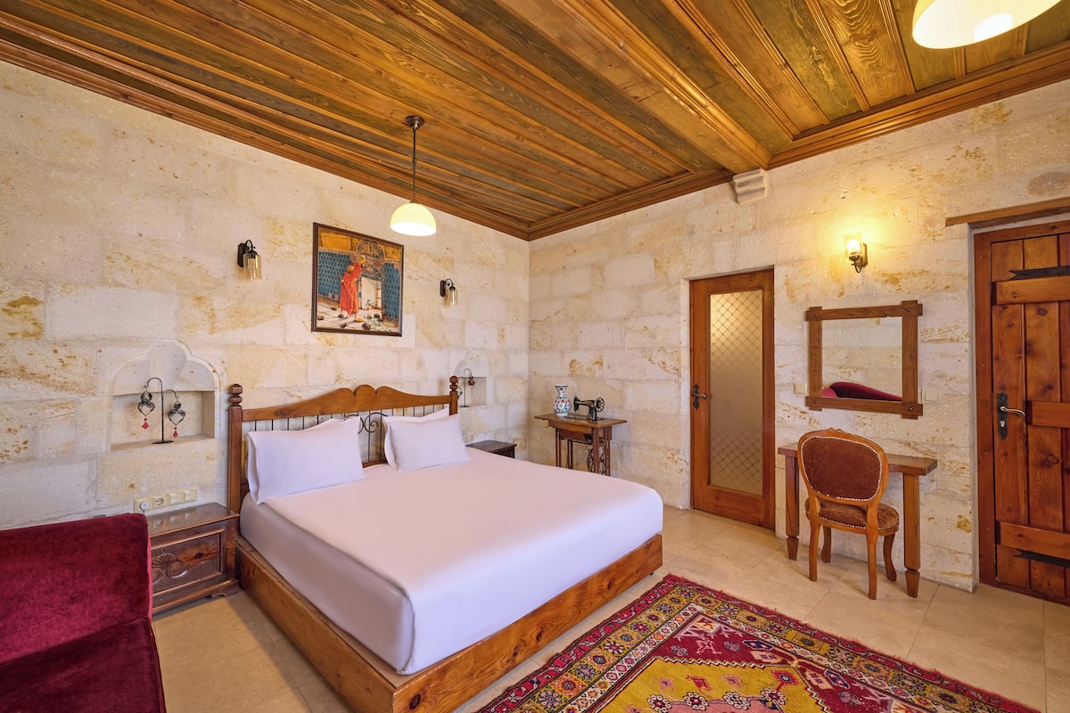 A bedroom with a wooden bed, a red chair, a small table, and a mirror.