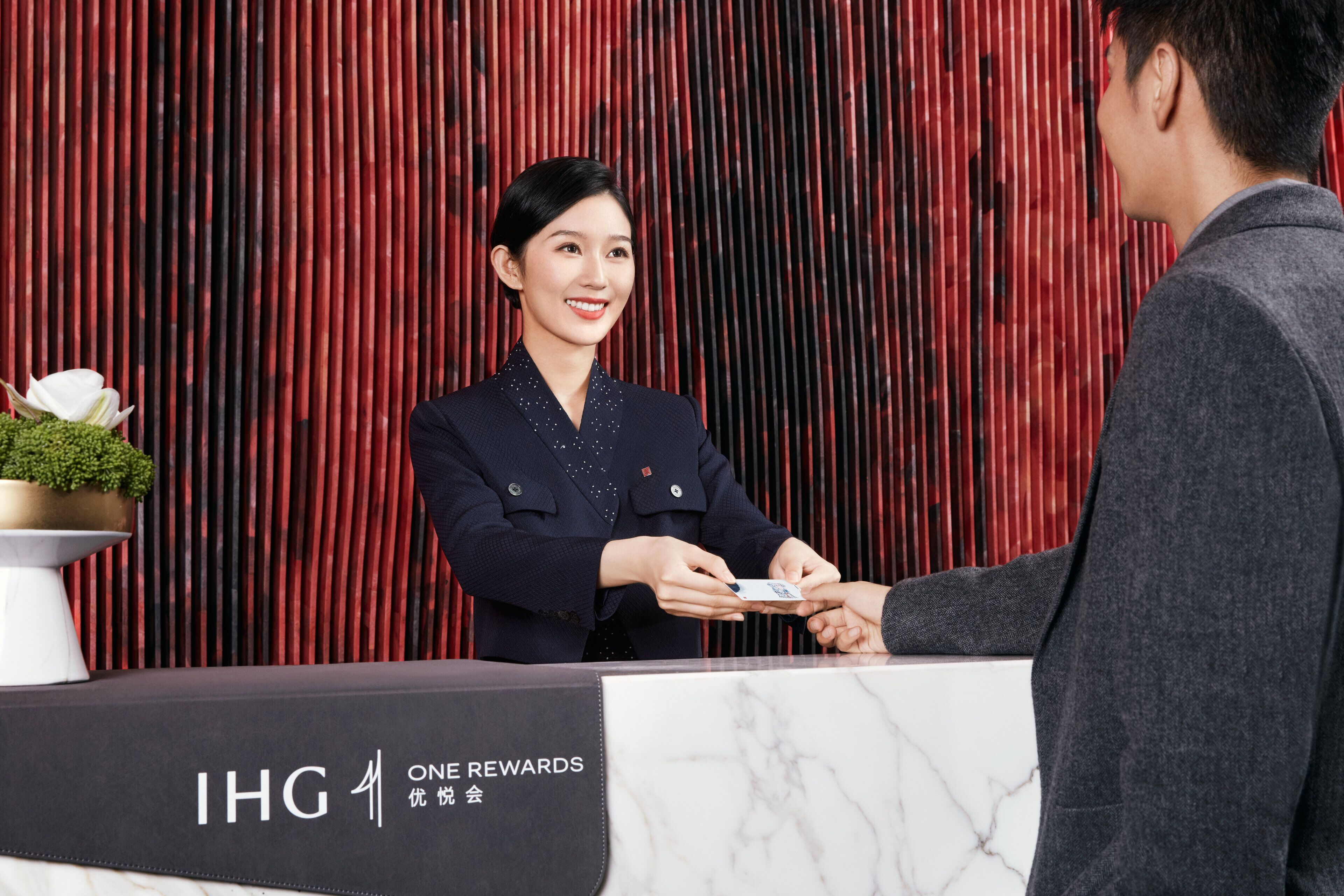 A reception desk with a marble top and a red vertical backdrop.