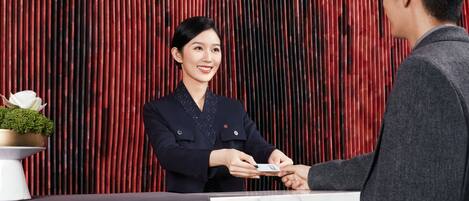 A reception desk with a marble top and a red vertical backdrop.