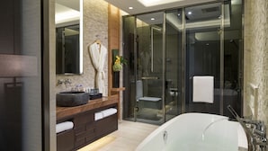 Een moderne badkamer met een groot bad, een rond wastafel en een douchecabine met glazen wanden.