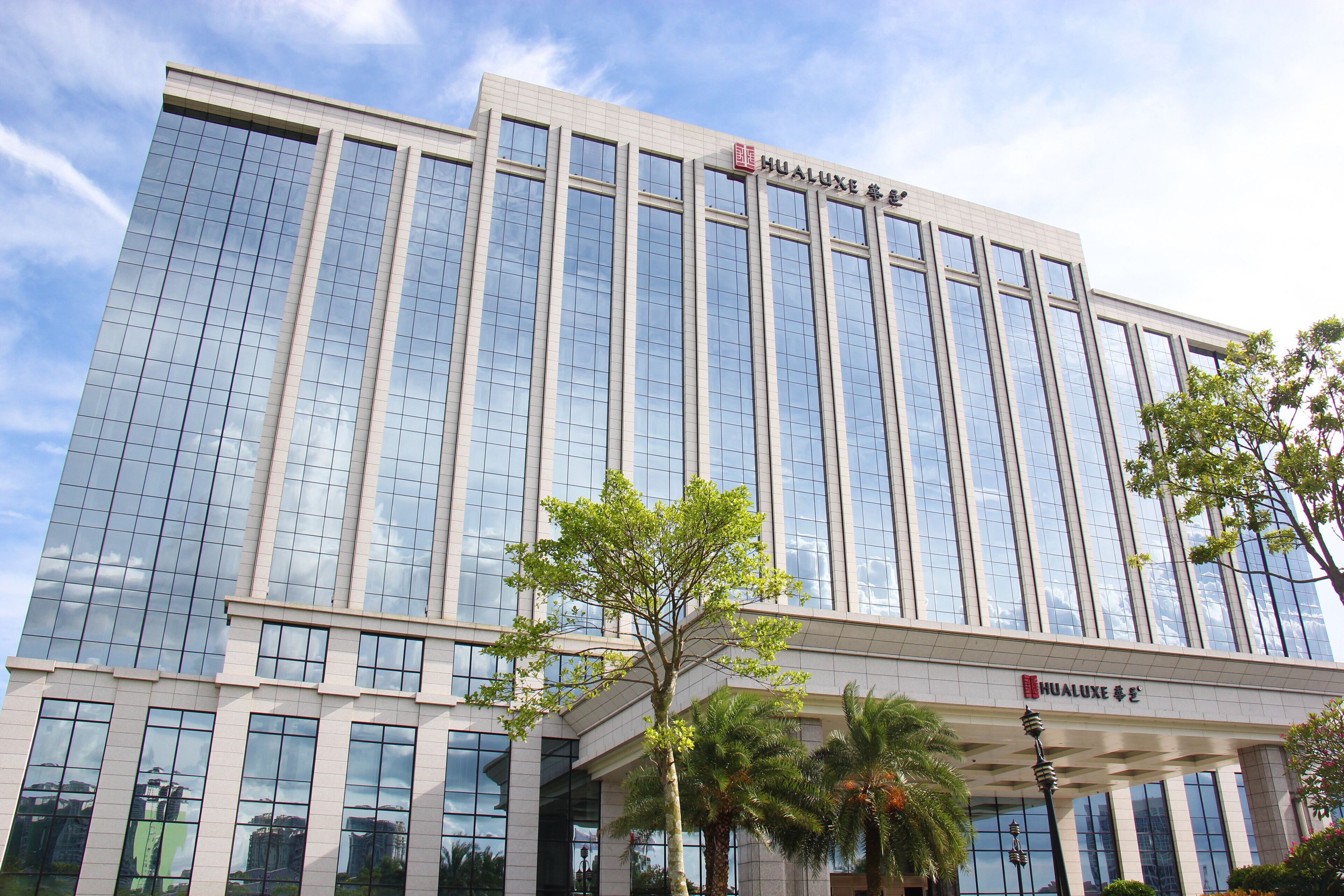 A modern building with a glass facade and a sign that reads "HUALUX".
