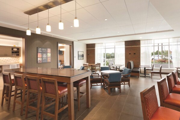A modern hotel lobby with a bar area, seating arrangements, and large windows offering views.