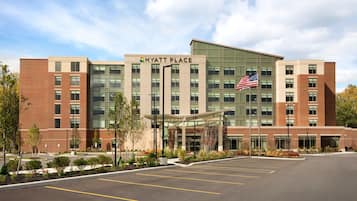 A modern Hyatt Place hotel with a parking lot and a landscaped entrance.