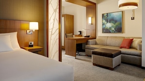 Une chambre d’hôtel avec un lit, un bureau, un canapé et un tableau au mur.