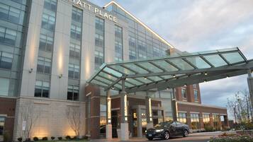 A modern hotel with a glass entrance and a covered walkway.