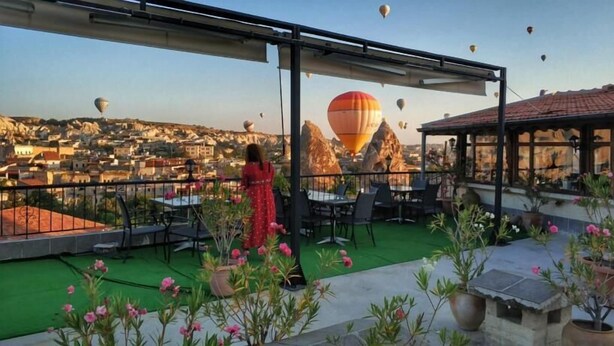 Una terraza en la azotea con vistas a un paisaje urbano y globos aerostáticos.