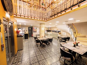 A hotel lobby with a grand staircase, a dining area with tables and chairs, and a kitchen area visible through a glass partition. - Diamond Royal Hotel (Istanbul)
