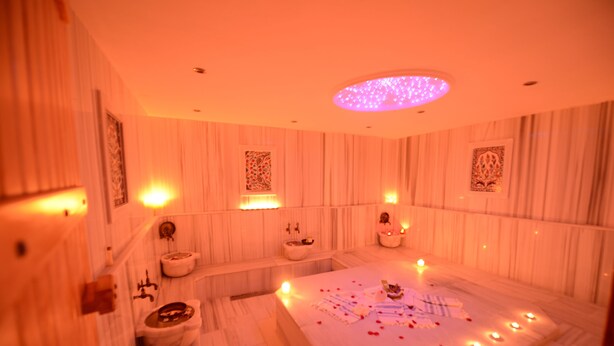 A spa room with a large bathtub, multiple sinks, and decorative candles. - Diamond Royal Hotel (Istanbul)