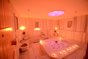A spa room with a large bathtub, multiple sinks, and decorative candles.