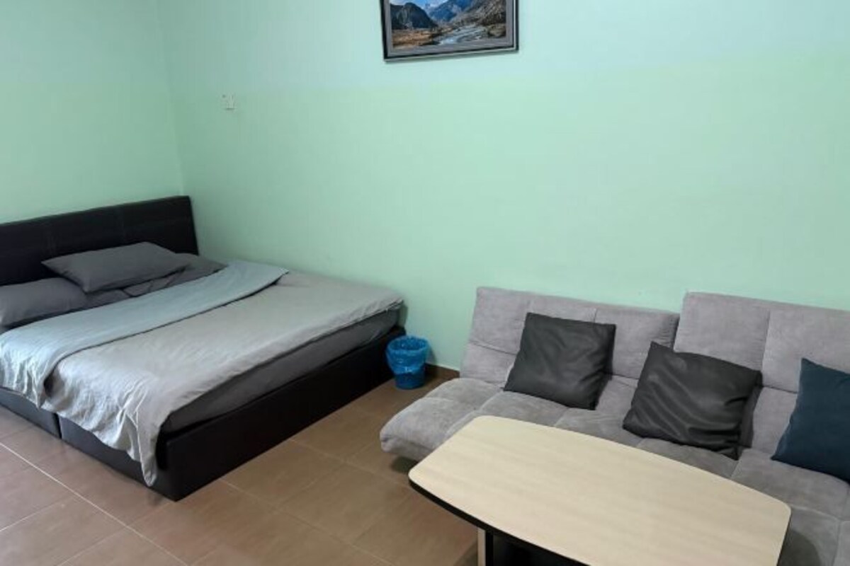 A room with a bed, a sofa, a small table, and a picture on the wall.