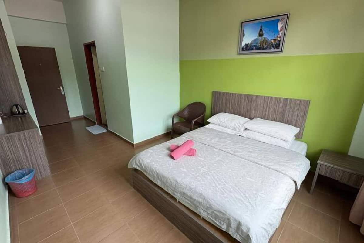 Una habitación de hotel con una cama, una silla, una mesita y un cuadro en la pared.