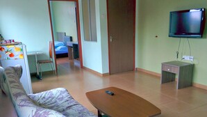 A living room with a sofa, a coffee table, a TV, and a desk. - Kea Valley Hotel Apartment (Brinchang)